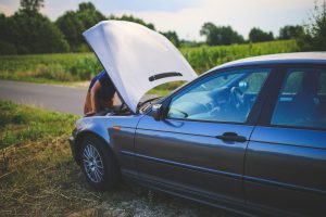 Parked car with man looking under bonnet